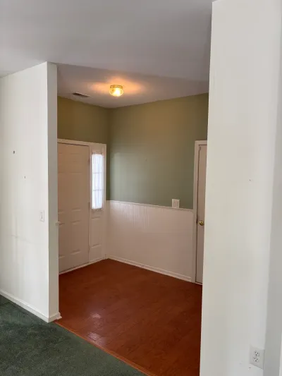 Entryway with green walls, white wainscoting, and a glass-paned exterior door before renovation.