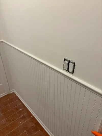 Hallway wainscoting installation in progress with an unfinished switch plate cutout above the beadboard trim.