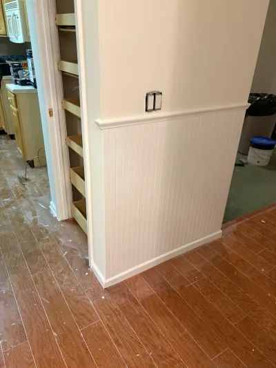 Kitchen under renovation with new beadboard wainscoting and exposed pull-out pantry shelving.