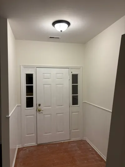 A finished entryway with a white paneled front door, sidelight windows, and beadboard wainscoting.