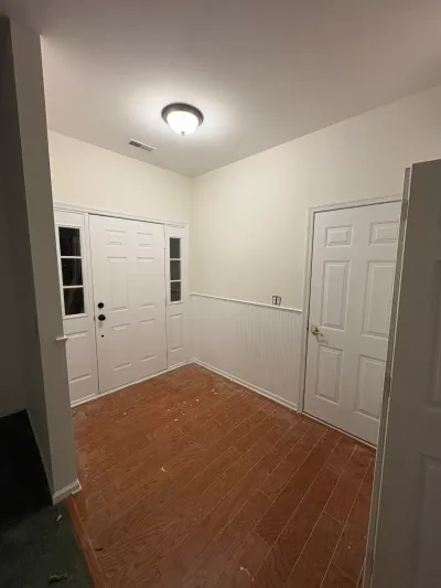 A finished entryway with wood flooring, white wainscoting, and a paneled front door with sidelights.