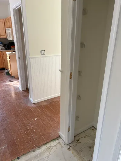 A kitchen and hallway under renovation with unfinished flooring, wainscoting, and an open closet.