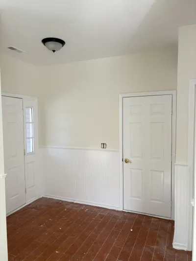 A newly finished entryway with wainscoting, wood-look tile floor, and white paneled doors.