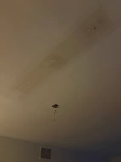 Ceiling with a large water stain and an exposed electrical wire hanging from a light fixture box.