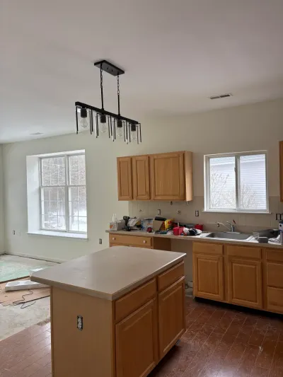 Kitchen mid-renovation with oak cabinets, laminate counters, and construction debris on the surfaces.
