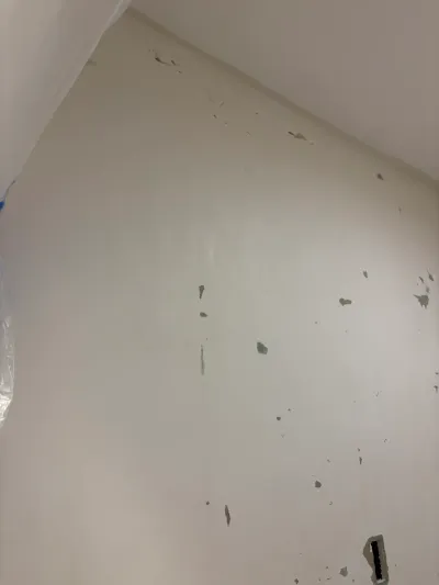 Close-up of a sloped wall and ceiling with scattered drywall patch marks during renovation prep.