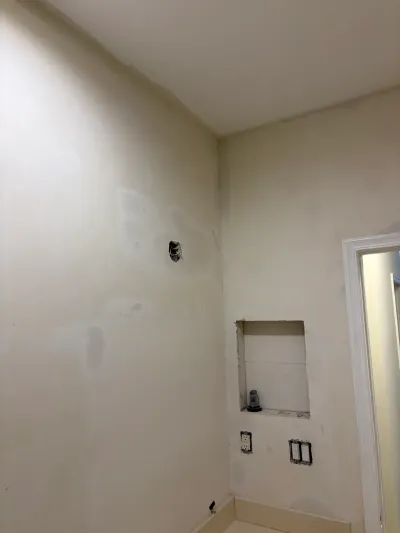 Bathroom wall mid-renovation with drywall, a rough-in shower niche, and exposed electrical boxes.