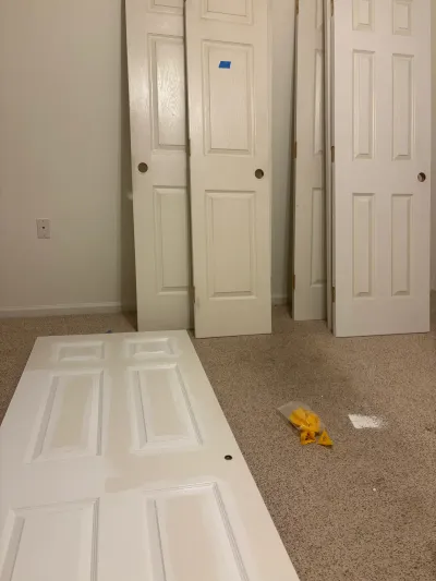 Several white paneled interior doors removed and leaned against a wall during a home renovation.