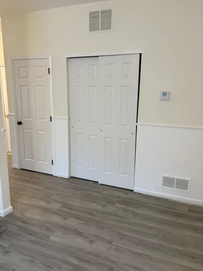Hallway with beadboard wainscoting, gray plank flooring, and white paneled closet and entry doors.