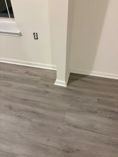 Newly finished room with gray wood-look vinyl plank flooring, white trim, and a corner column.