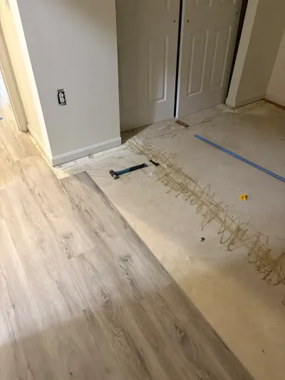 Partially completed vinyl plank flooring installation next to bare subfloor and closet doors.