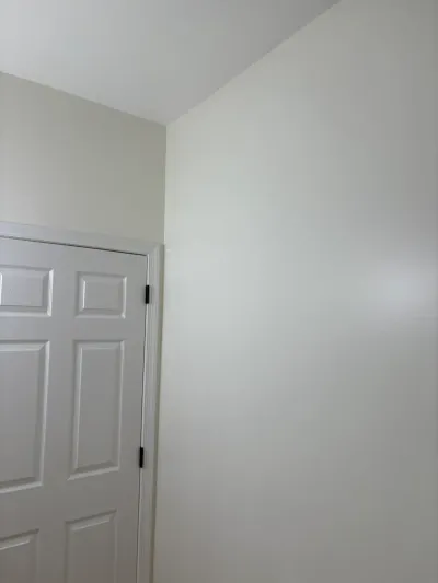 A white paneled door beside a wall with a sloped ceiling in a finished hallway.