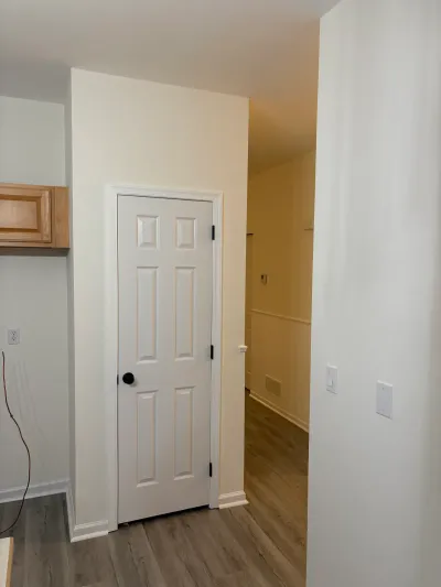 Kitchen corner with a white paneled closet door and a hallway leading to a sloped ceiling area.