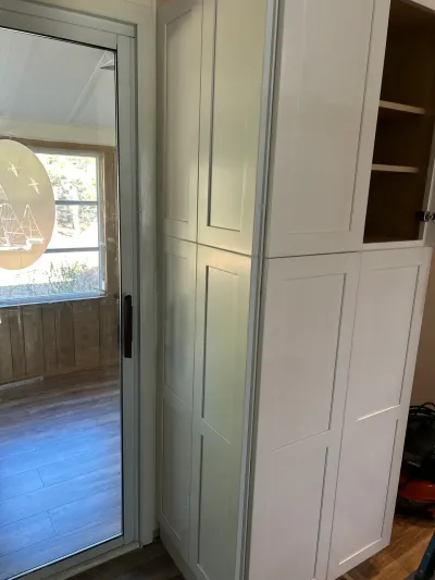 Tall white shaker pantry cabinets stand beside a glass door etched with a sailboat design.