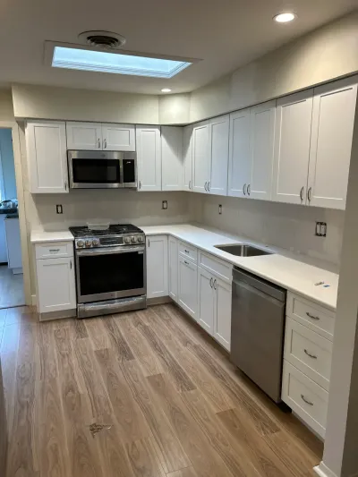 A kitchen mid-renovation with new white cabinets and appliances installed but the backsplash tile not yet added.