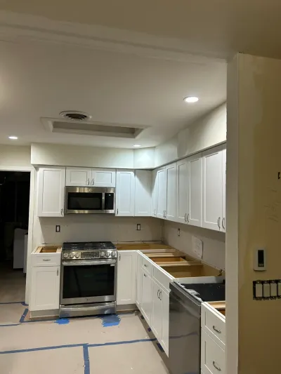 Kitchen under renovation with white shaker cabinets installed but countertops and backsplash still unfinished.