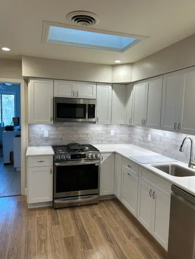 Finished kitchen with white shaker cabinets, quartz counters, subway tile backsplash, and a skylight overhead.