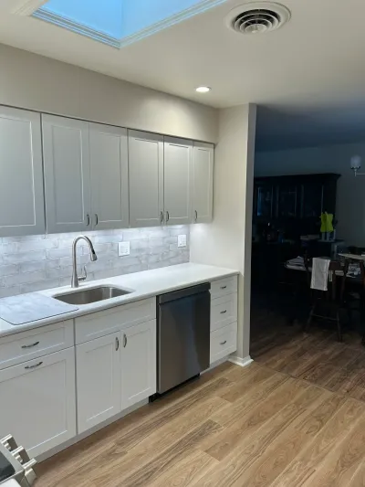 Renovated kitchen with gray shaker cabinets, quartz counters, subway tile backsplash, and a skylight over the sink.