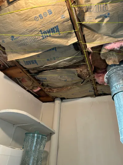 Basement ceiling opened up to reveal exposed insulation, joists, and ductwork during a renovation.