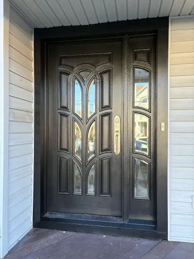 A black front door with arched glass panels and a matching sidelight, set on a covered porch.