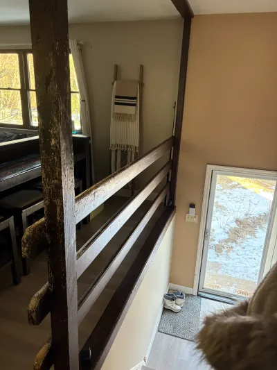 View from a loft railing down toward a glass entry door with shoes on the mat below.