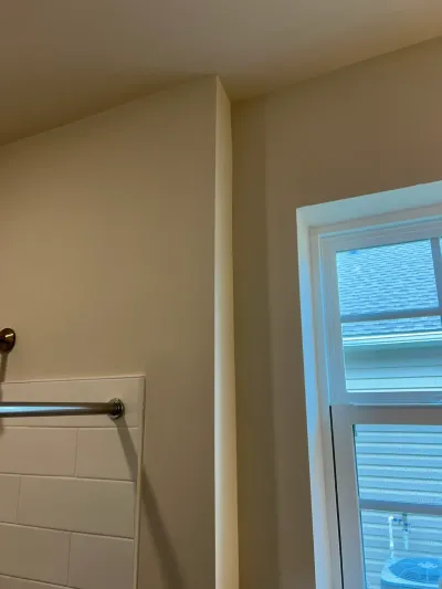 Bathroom corner with a sloped ceiling, subway tile, a towel bar, and a window overlooking a rooftop.