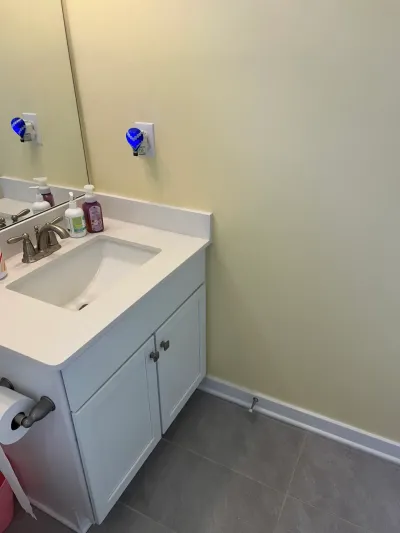 White shaker vanity with integral sink, brushed nickel faucet, mirror, yellow walls and gray tile floor.