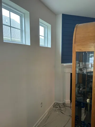 Living room corner with greige walls, white-trimmed windows and a fireplace under a navy shiplap accent wall.