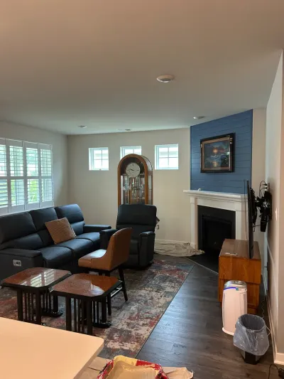 Living room with navy shiplap fireplace wall, white mantel, dark wood floors and drop cloths from ongoing work.