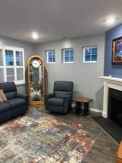 Finished basement living room with navy shiplap fireplace wall, gray walls, vinyl plank floor and navy recliners.