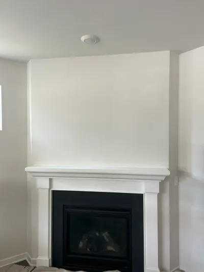 Freshly painted white fireplace chase with craftsman mantel and black gas insert, mid-remodel
