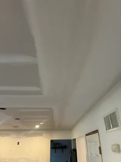 Freshly taped drywall ceiling with recessed light cans and a soffit in a room under renovation.