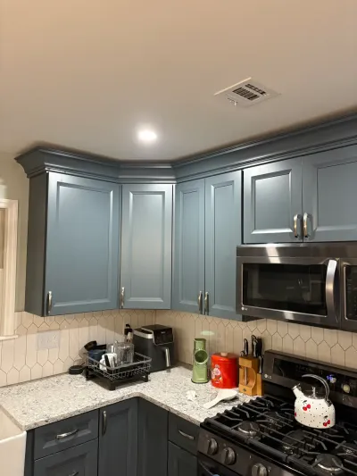 Blue-gray raised-panel kitchen cabinets with granite counters, cream picket tile backsplash and stainless range.