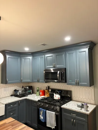 Kitchen with blue-gray raised-panel cabinets, granite counters, picket tile backsplash and black gas range.