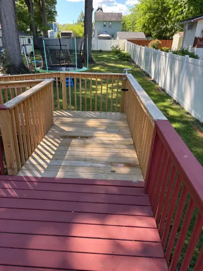 Multi-level backyard wood deck with red-stained upper level and new natural wood lower landing.