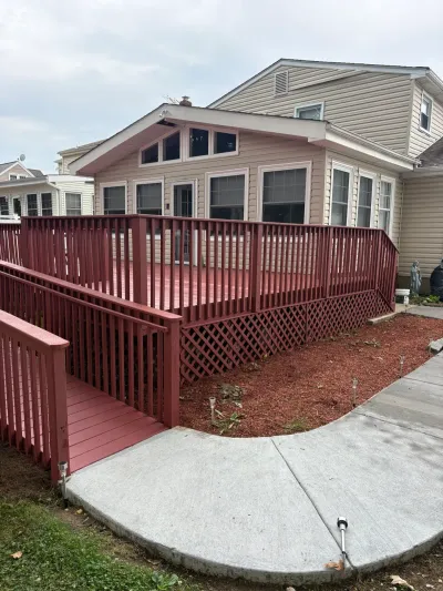 Freshly painted red wood deck with lattice skirting and an access ramp leading to a concrete walkway.