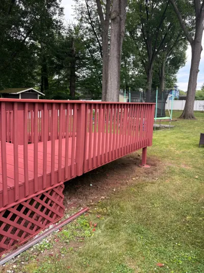 Raised backyard deck stained barn red with vertical baluster railing and diagonal lattice skirting.