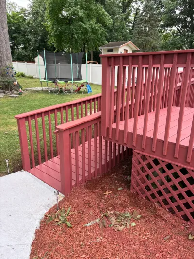 Freshly stained red backyard deck with balusters, stairs, lattice skirting, and mulch bed