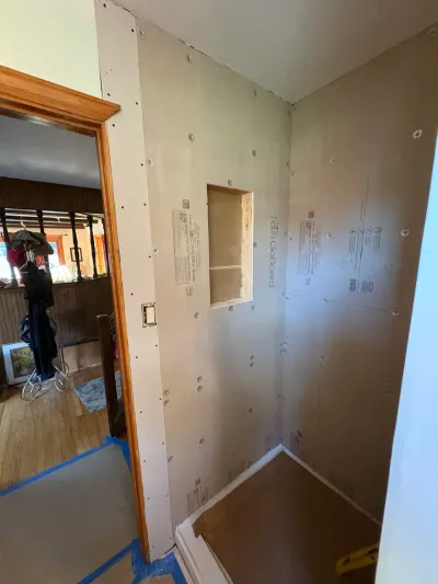 Shower alcove under construction with GoBoard backer board walls, framed niche, and white shower pan.