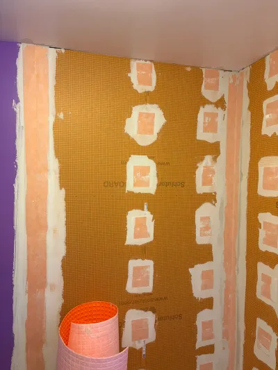 Shower walls being prepped with waterproof tile backer board and taped seams before tiling.