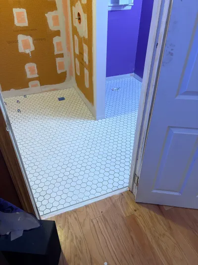 Bathroom under renovation with new hexagon tile flooring and waterproofing membrane on the walls.