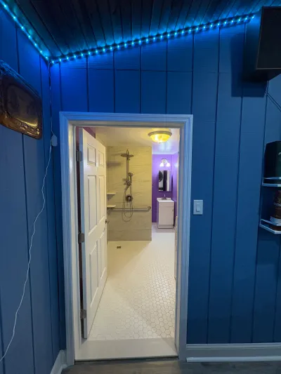 View through an open door into a finished bathroom with a curbless tiled shower and hexagon tile floor.