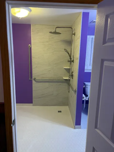 Accessible curbless shower with grab bars, rainfall head, and purple accent walls.