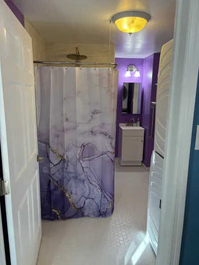 Small purple-accented bathroom with a marble-patterned shower curtain and hexagon tile floor.
