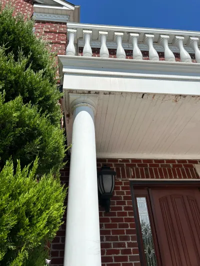 Close-up of a weathered white porch column and balustrade against a red brick entryway.