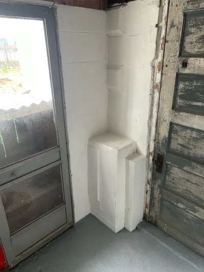 Worn entryway corner with a peeling painted door, storm door, and thickly painted masonry walls.