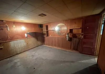Dim unfinished basement room with wood paneling, concrete floor, and exposed wiring.','layoutFeatures':[]}</br>{