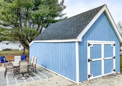 A blue board and batten shed with white trim and a gravel patio featuring outdoor furniture.