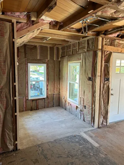 Unfinished room under construction with exposed insulation, framing, and rough electrical wiring.
