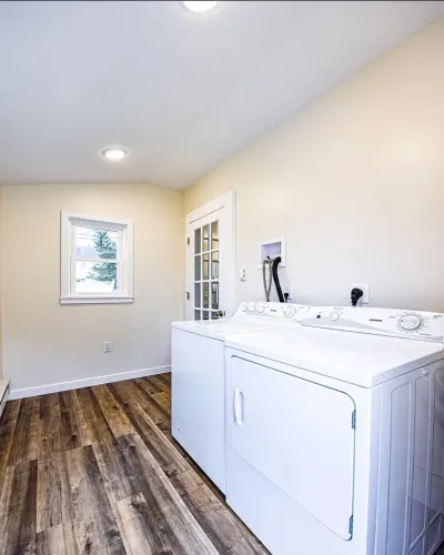 Bright laundry room with vaulted ceiling, wood-look flooring, and white washer and dryer.
